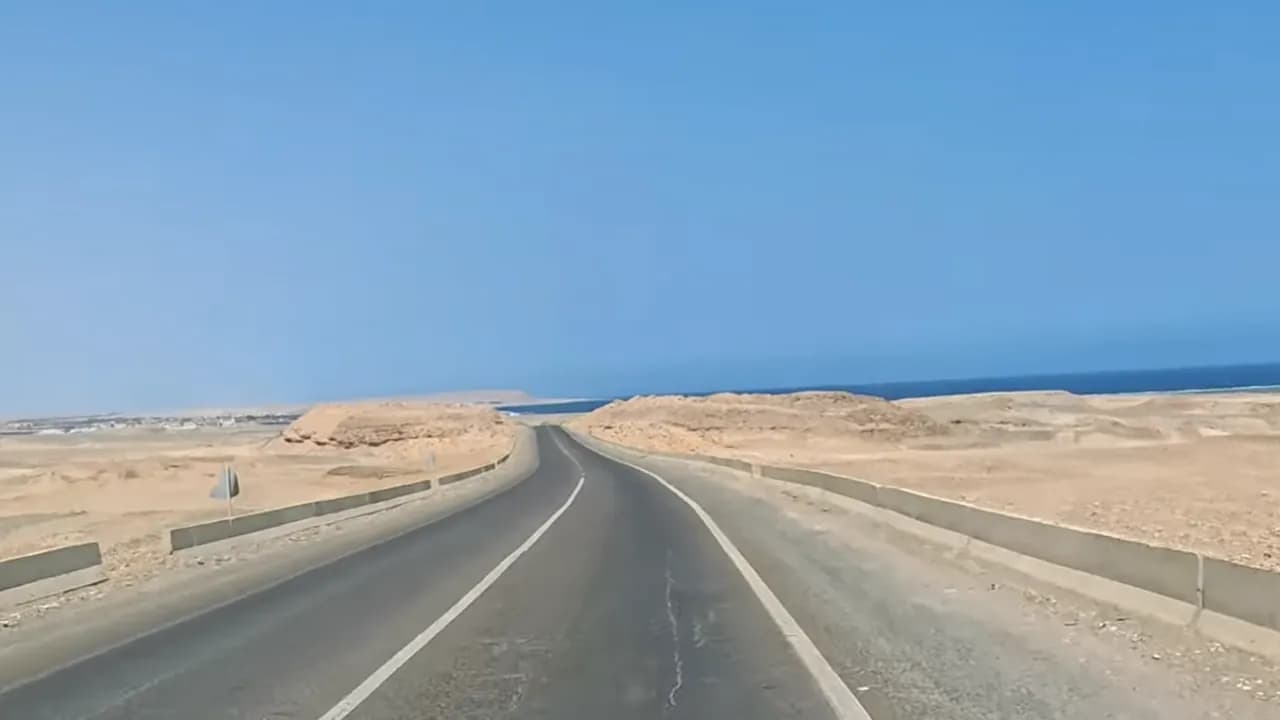 Asfaltweg door de woestijn met de Rode Zee aan de horizon op de kustroute ten zuiden van Hurghada